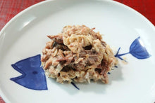 画像をギャラリービューアに読み込む, 熊野灘や伊勢志摩産の天然魚の無添加レトルトフレークお魚ごはんがお皿に盛り付けられている。袋の上から指でほぐした小魚がフレーク状になっており、骨もワタも入っている様子が確認できる。